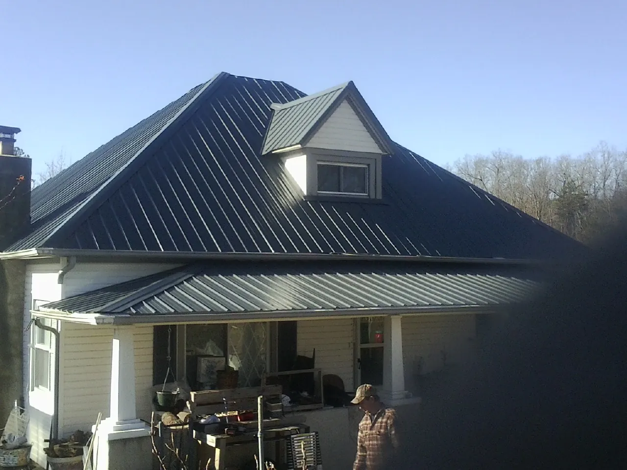 Dark blue standing seam metal roof with a dormer above a front porch in Mesquite