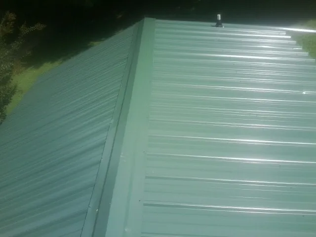 New green metal panels meeting at the ridge of a roof — Flat Roof Repair work by our crew in Mesquite